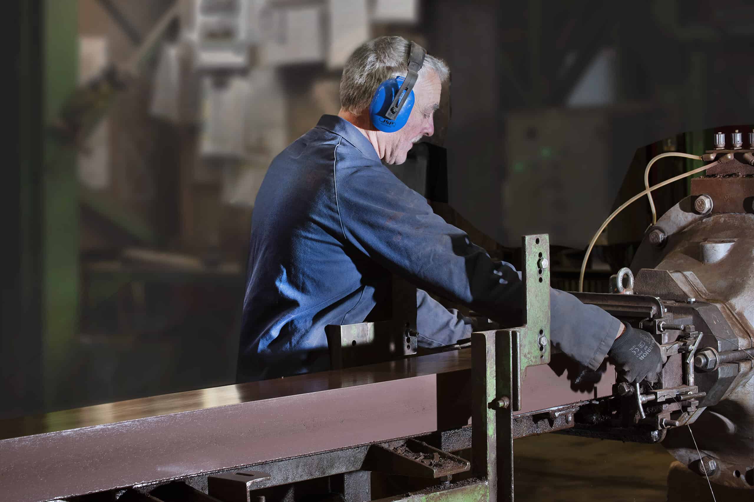 photo of a man in ear defenders working at machine